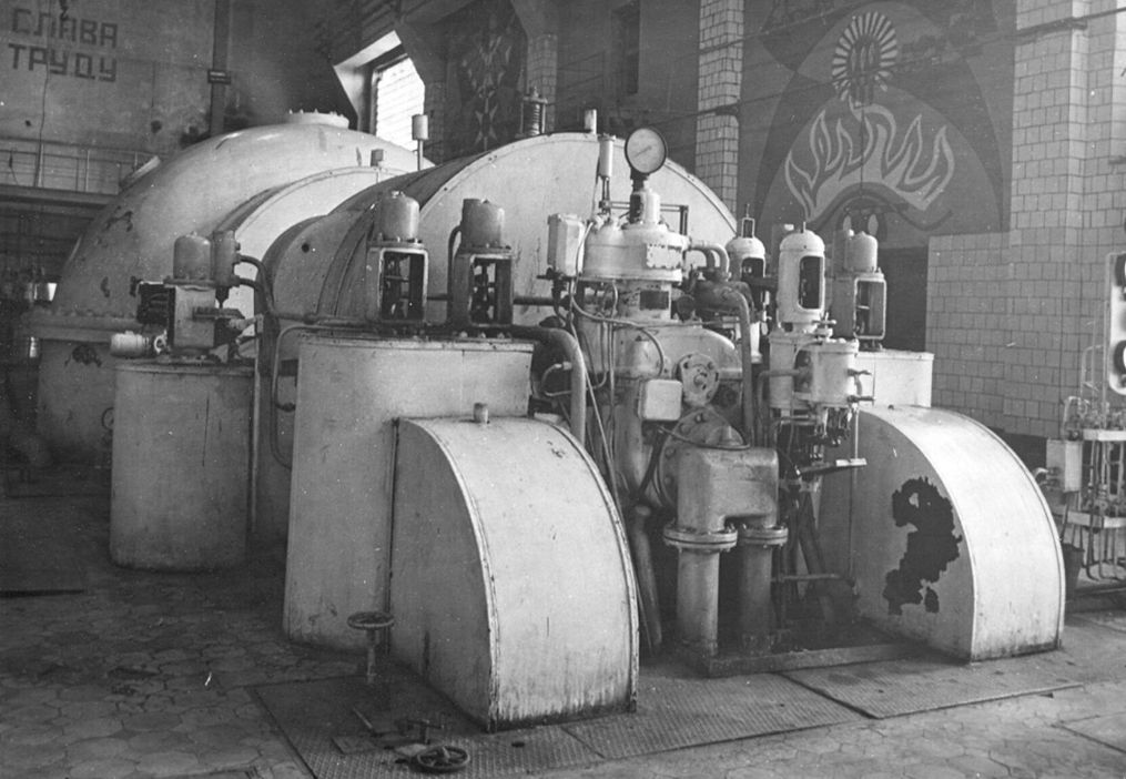 Фото сделано в историческом корпусе ижевской ТЭЦ-1. Данная турбина вырабатывала электричество в годы войны и продолжала это делать вплоть до 1985 года. За ней видно настенные панно.
